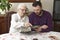 Old woman with her grandson sitting at the table in the living room and watching old photos.