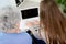 Old woman at home with cheerful young girl spending time together with laptop computer