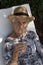 old woman looking at the camera and drinking mate in the garden of her house