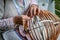 Old woman in national costume make local wicker basket. Traditional handicrafts concept. Latvia .