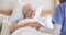 Old woman, nurse hands and support in bed at home, care and help in rehabilitation. Happy caregiver, bedroom and comfort