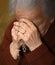 Old woman praying and holding silver rosary