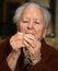 Old woman praying and holding silver rosary