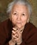 Old woman praying and holding silver rosary