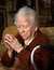 Old woman praying and holding silver rosary