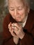 Old woman praying and holding silver rosary