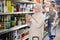 Old woman purchaser choosing cool drink in big supermarket