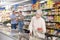 Old woman purchaser choosing frozen product in big supermarket