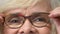 Old woman putting eyeglasses on closeup, eyesight check, ophthalmology health
