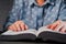 Old woman reading thick book at home. Grandmother with Bible. Concentrated elderly pensioner with wrinkles on hands