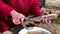 old woman's hands cleaning a frozen fish carcass