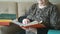 Old woman sitting on a chair reading a thick book