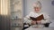 Old woman sitting in wheelchair reading book, searching eyeglasses, bad vision