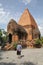 The old woman is standing beside Ponagar Temple Towers of Cham people