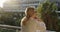 An old woman stands on a balcony in summer and enjoys a beautiful city.