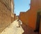 An old woman wiyh a white traditional veil walking in the street of the oasis of Figuig