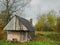 Old wooden barn by a forest. Country side. Cloudy sky. Small farm building of warehouse.
