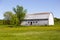 Old wooden barn set in field covered in dandelion in bloom with wooded area in the background