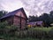 An old wooden Belarusian hut on a farm in the evening, cloudy sky