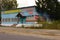 Old wooden blue barrack made of wooden planks with porch and signs in Russian - CAFETERIA, CANTEEN, PRODUCTS SHOP beside the road