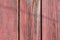 Old wooden boards with peeling red paint. Background of wood texture with peeling paint on a sunny day