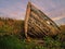 Old wooden boat ashore in a field.