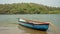 Old wooden boat on the shore of a tropical river. A wooden fishing boat sways on the waves