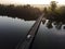 Old wooden bridge with rails over river against sunset backgroun