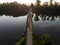 Old wooden bridge with rails over river against sunset backgroun