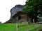 Old wooden cabin in a meadow at the foot of a rock cliff