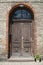 Old wooden carved double door, brick building entrance.