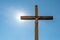 An old wooden Catholic cross against the background of the sun and clear blue sky. Religion and service to God as a path to