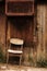 Old wooden chair next to a wooden plank wall with a door and a dovecote