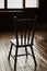 Old wooden chair stands in front of window in the spotlight in empty dark room