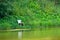 An old wooden chair stands on the shore of a pond