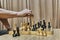 Old wooden chess pieces on chessboard. Hand of adult man making move with white queen