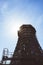 Old wooden cooling tower with sun flare on blue sky