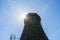 Old wooden cooling tower with sun flare on blue sky