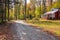 Old wooden cottage along a winding forest road on sunny autumn day