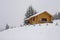 Old wooden cottage on a hill covered in the snow on a gloomy day in winter
