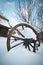 Old wooden cottage and wooden Romanian wheel covered by snow. Cold winter day at countryside. Traditional Carpathian mountains