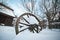 Old wooden cottage and wooden Romanian wheel covered by snow. Cold winter day at countryside. Traditional Carpathian mountains