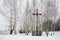 Old wooden cross in a small park of birches in winter