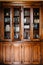 An old wooden cupboard with doors that can be locked with keys and a shallow grate for glass.