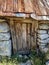 Old wooden decayed door on the stone mountain cottage house with old lock and traditional stone walls. Rusty roof on top and