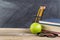 Old wooden desktop with green apple and reading materials