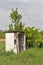 Old wooden dilapidated toilet in a village among the trees.