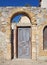 Old wooden door in an arched frame in an ancient stone wall on a sunlit street in nicosia cyprus