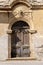 Old wooden door archway aged front entrance of medieval building decorated with stone on stucco background