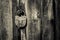 The old wooden door is closed with a large metal padlock.  Black and white photo. Concept: secrets of antiquity.